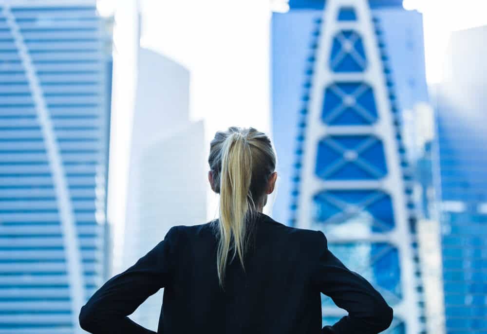 Mulher olhando para uma cidade do alto de um prédio