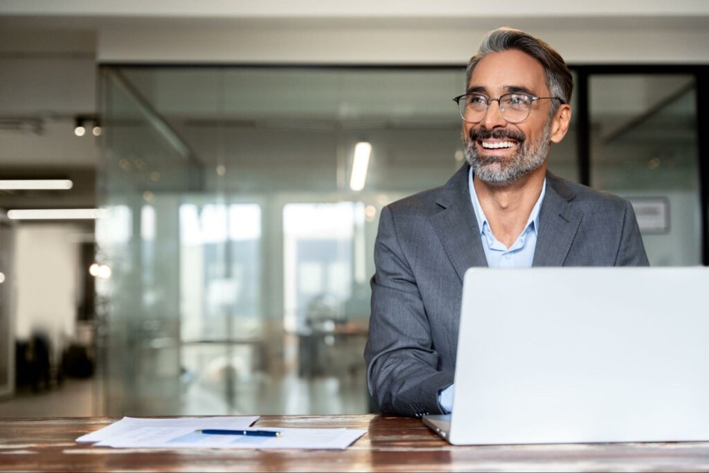 Homem sorrindo mexendo no notebook