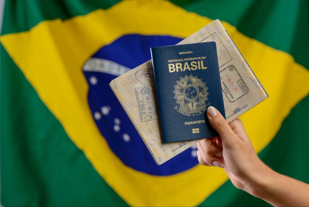 Homem segurando passaporte brasileiro com bandeira do Brasil atrás